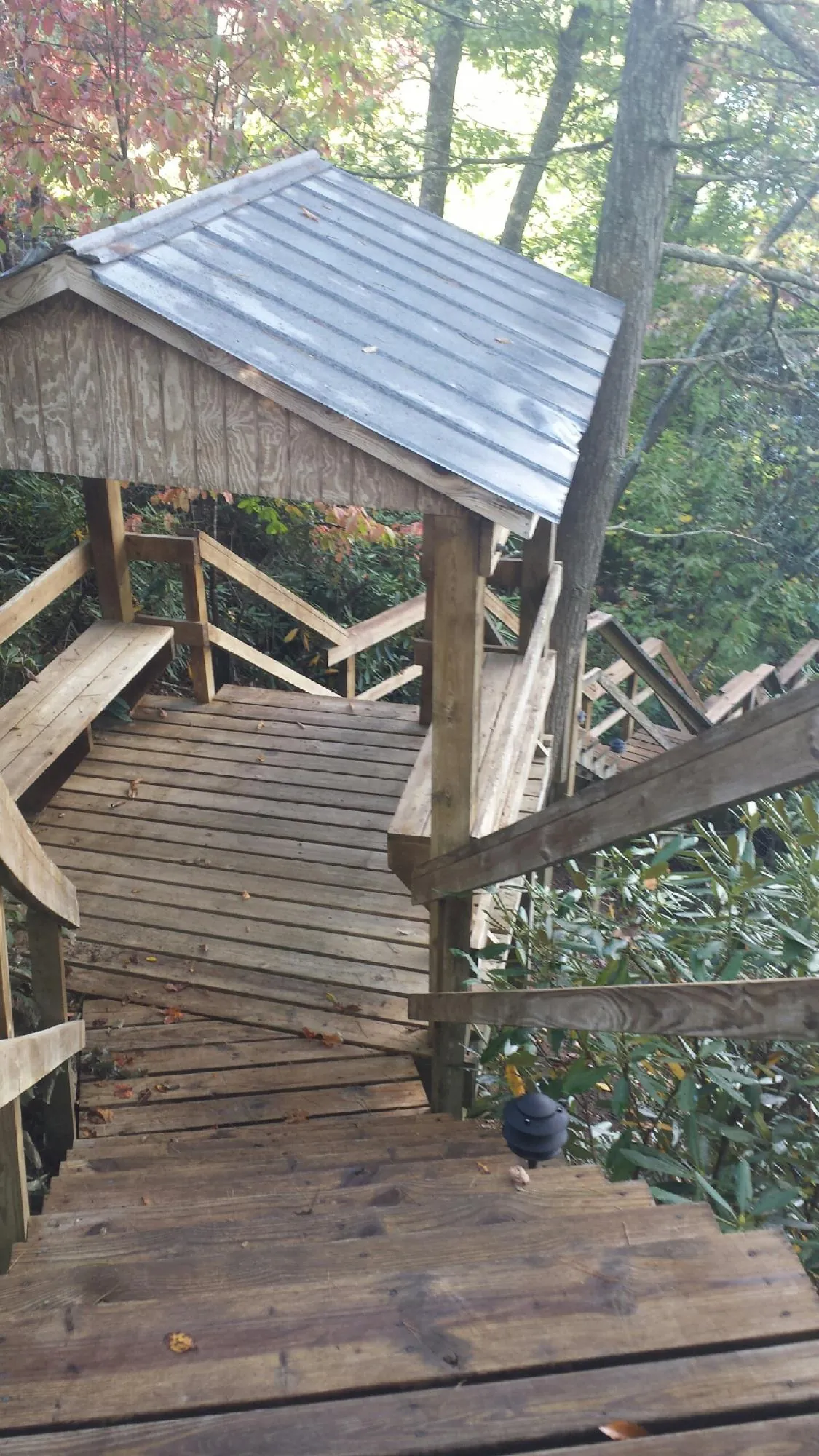 Metal roofed shelter over wooden steps on a wooded walkway — Skylight Repair & Installation work by our crew in Joliet